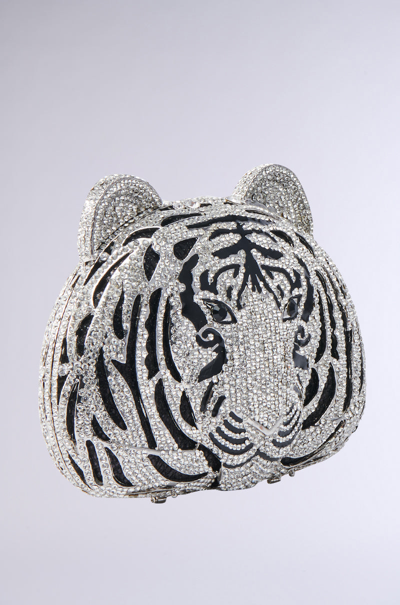 The HEAR ME ROAR BLING BAG is a jeweled clutch shaped like a tiger's head, embellished with silver and black crystals to accent its features, displayed on a plain light gray background.