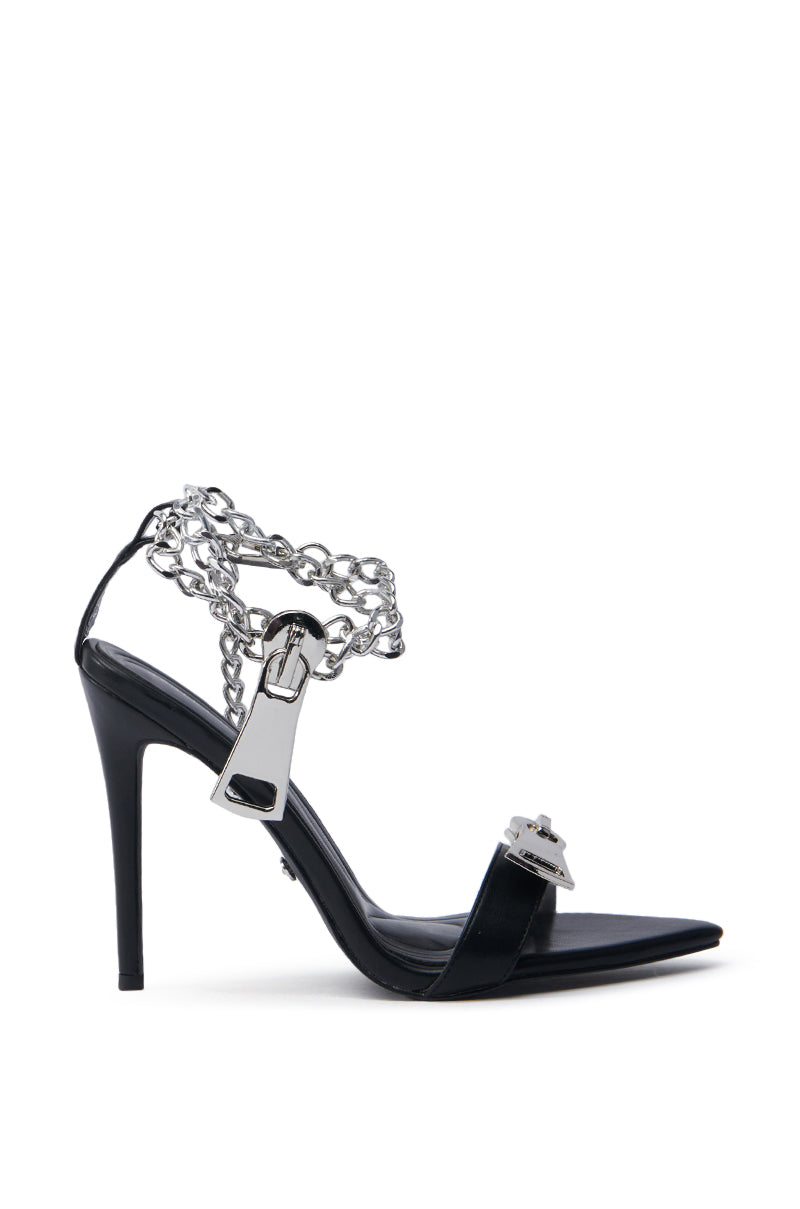 Discover the AZALEA WANG HORUS BLACK ZIPPER DETAIL SANDAL: an exquisite black stiletto featuring a pointed toe, crafted from faux leather with silver chain detailing and a metal buckle on the toe strap, effortlessly merging edgy elements with elegance.