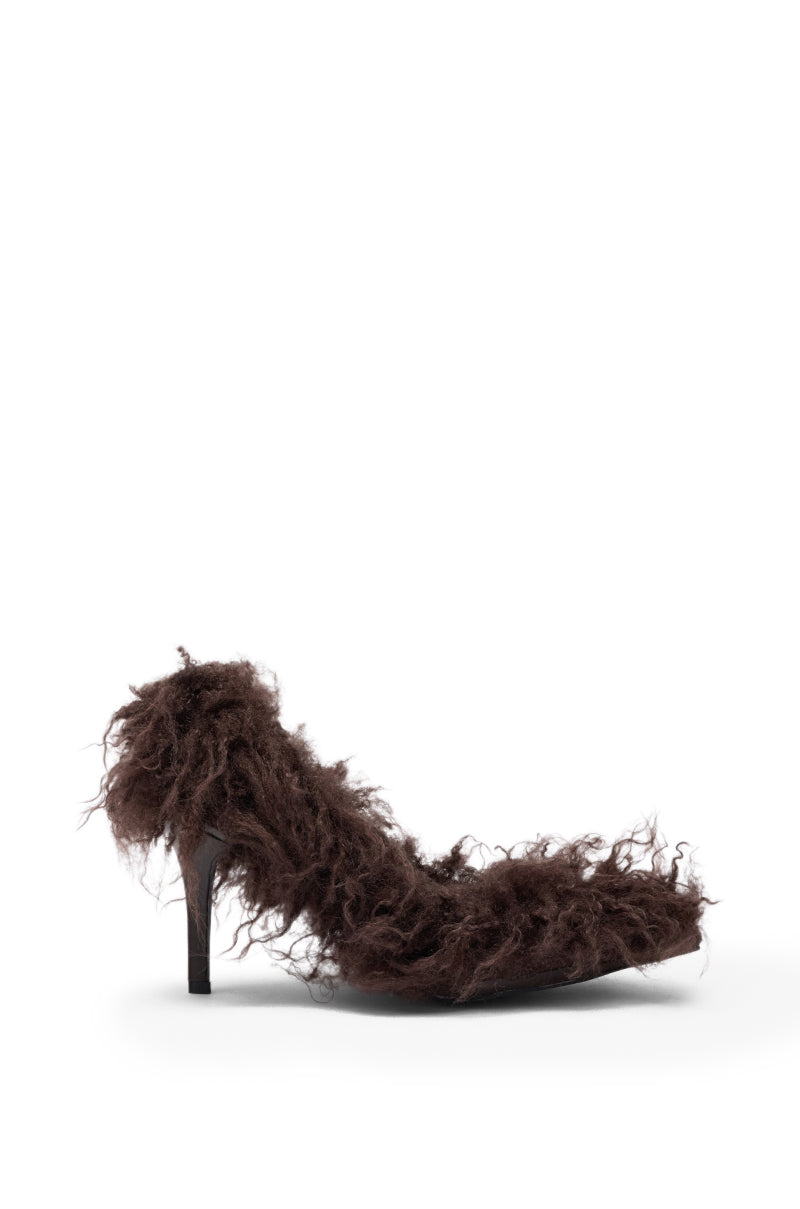 The AZALEA WANG JAMEEKA CHOCOLATE POODLE HAIR PUMP, a single pointed-toe stiletto covered in dark brown curly faux fur, is shown in profile against a white background.
