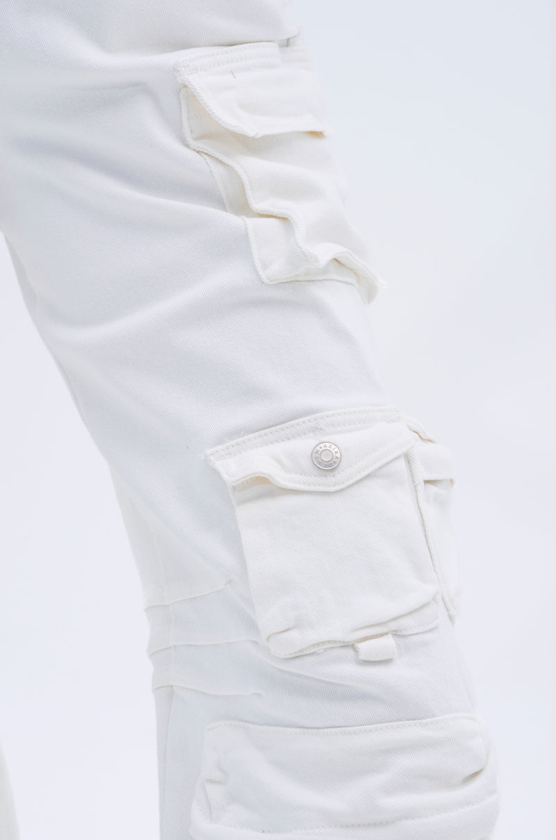 Close-up of the LINDSAY DENIM CARGO JUMPSUIT IN WHITE, highlighting multiple buttoned flap pockets and stitching details that showcase utility-inspired design and textured denim fabric.