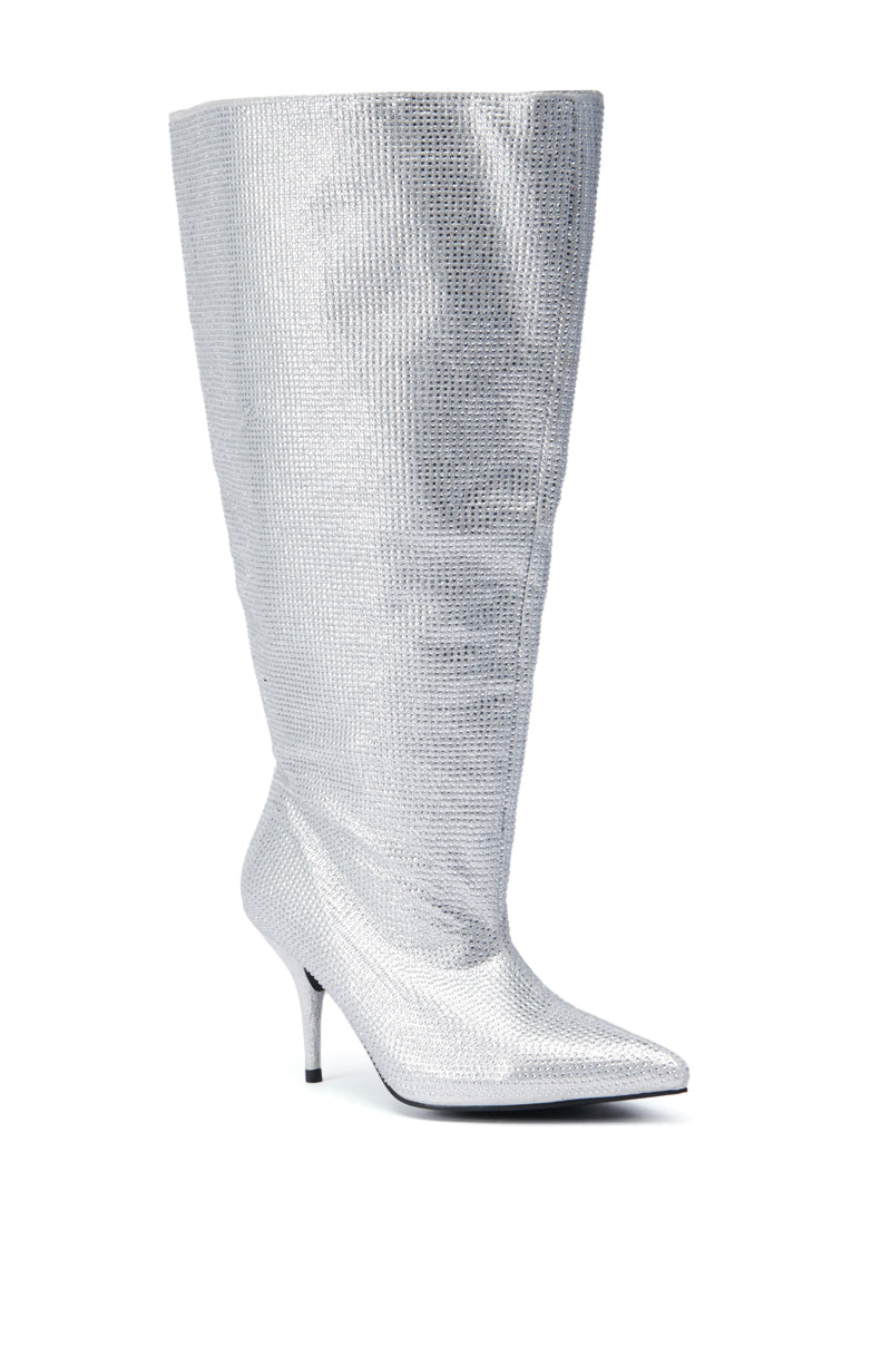The AZALEA WANG JARROW SILVER RHINESTONE BOOTIE is a spectacular knee-high boot with a pointed toe and stiletto heel, showcasing a glittering rhinestone textile upper against an elegant white backdrop.