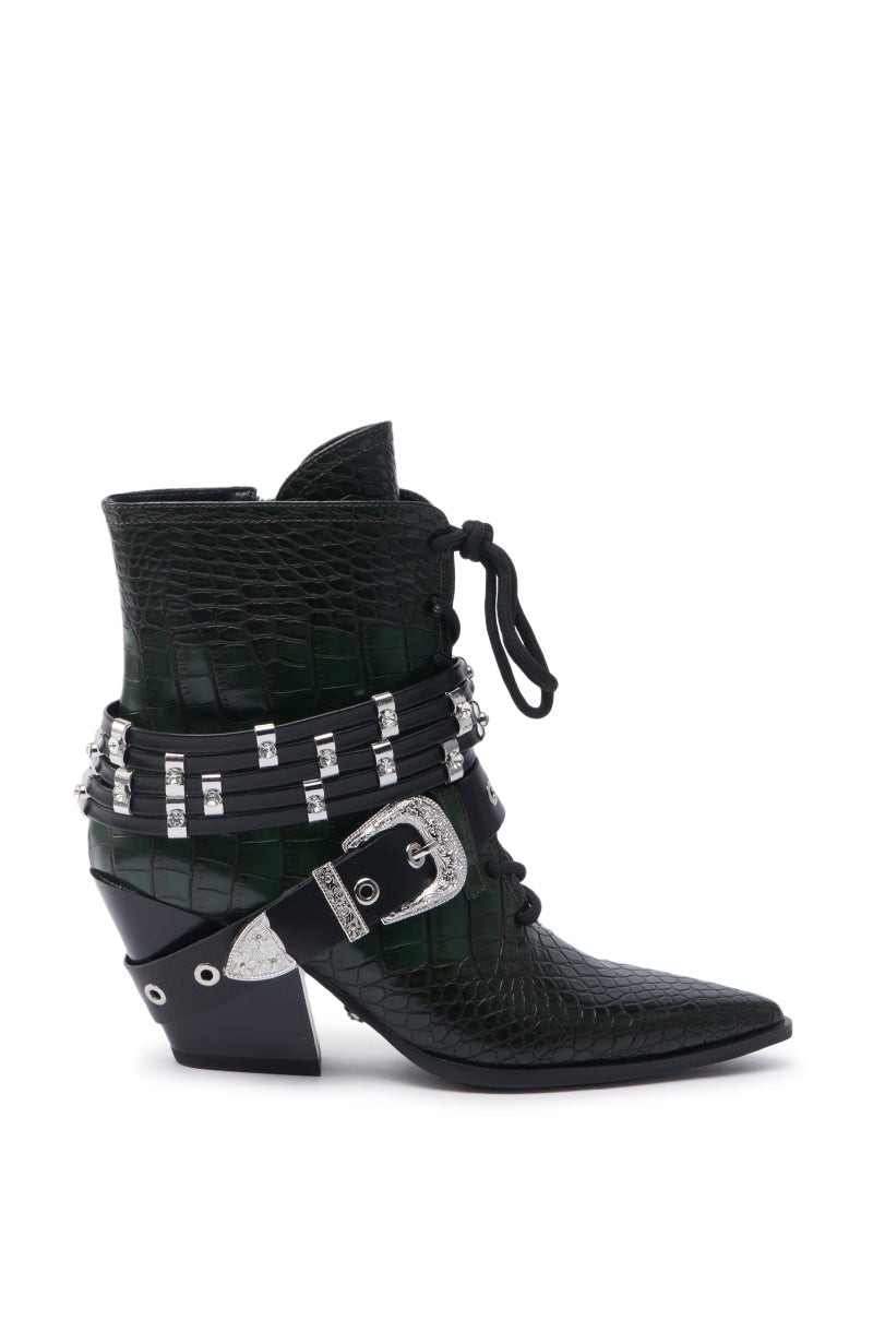 The AZALEA WANG JAVELIN GREEN WESTERN BOOTIE features crocodile-embossed leather in green, a pointed toe, chunky heel, silver buckle, grommets, laces, and studded straps that wrap around the ankle.