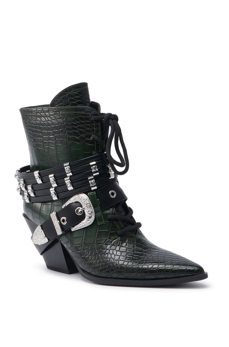The AZALEA WANG JAVELIN GREEN WESTERN BOOTIE is a dark green, crocodile-embossed bootie with a pointed toe, chunky heel, black laces, and multiple buckled straps accented by silver hardware and decorative studs.