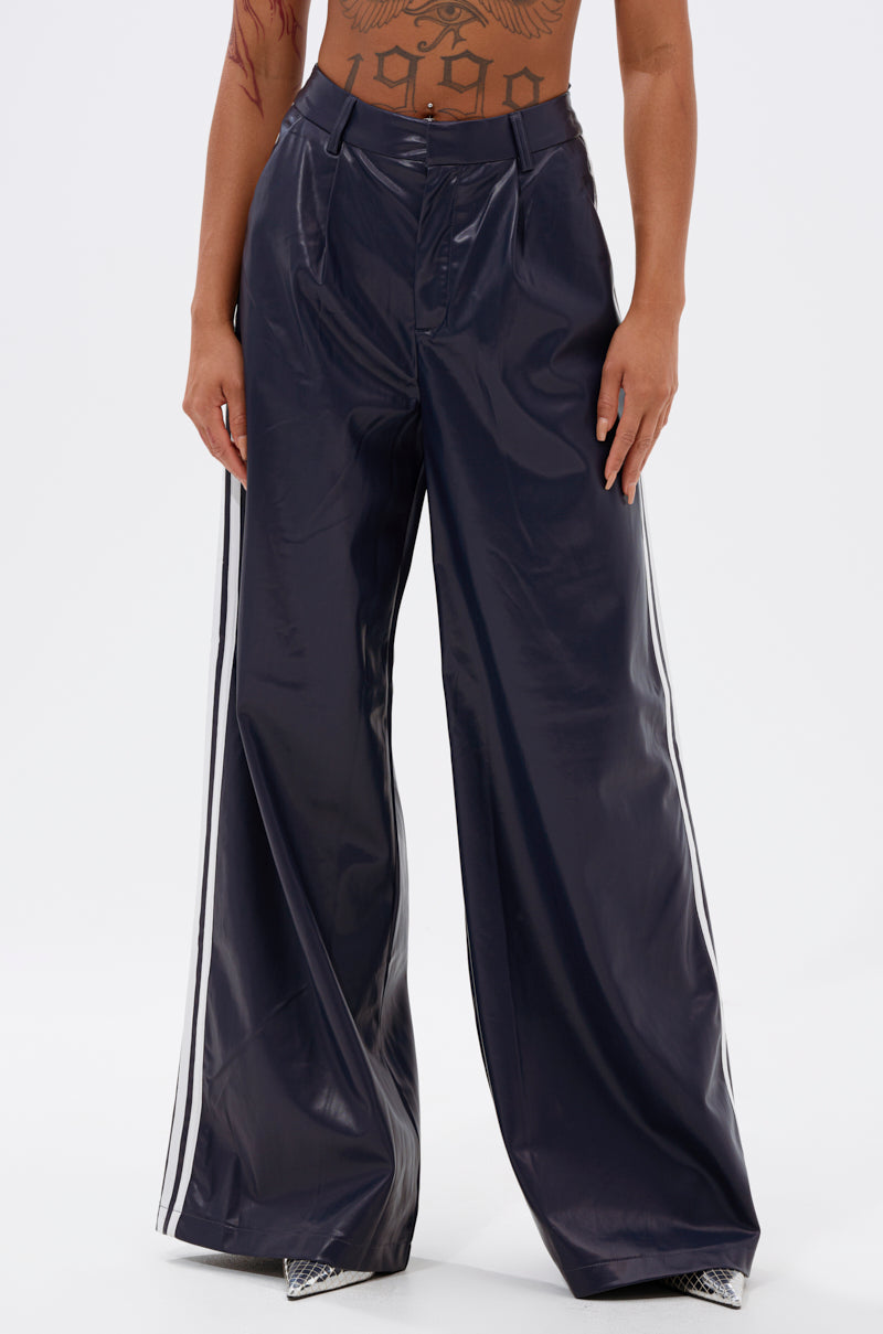Someone wears the DAYTIME LOVIN TROUSER IN NAVY—high-rise, wide-leg pants with athletic accent stripes—standing against a plain light background, showing only torso and legs.