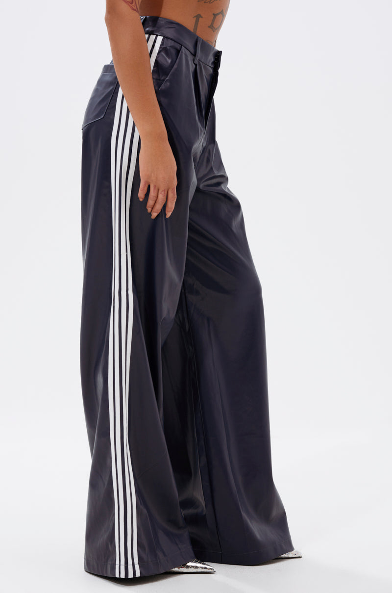 Model wearing the DAYTIME LOVIN TROUSER IN NAVY, a high-rise wide-leg pant featuring three white stripes down the sides; only lower torso and legs are visible against a plain white background.