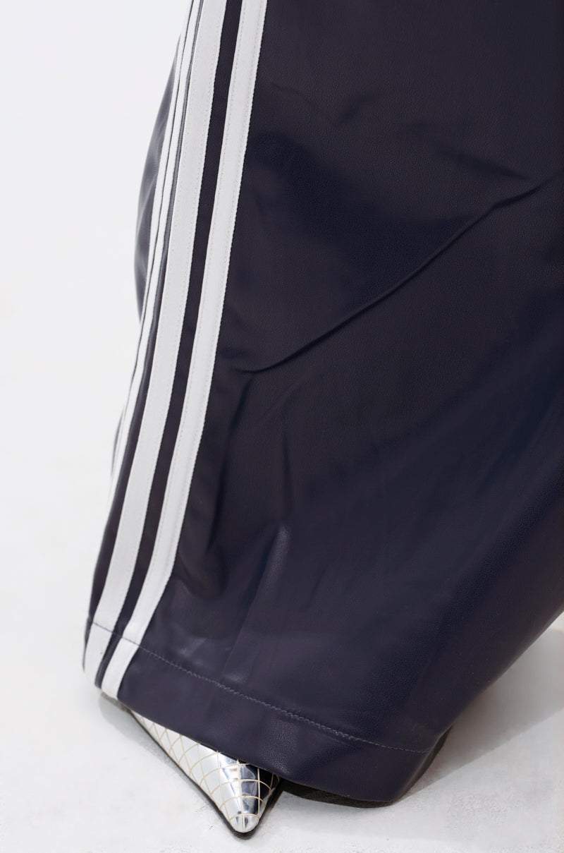 Close-up of DAYTIME LOVIN TROUSER IN NAVY, featuring white side stripes, partially draped over a pointed silver geometric-patterned shoe against a plain light background.