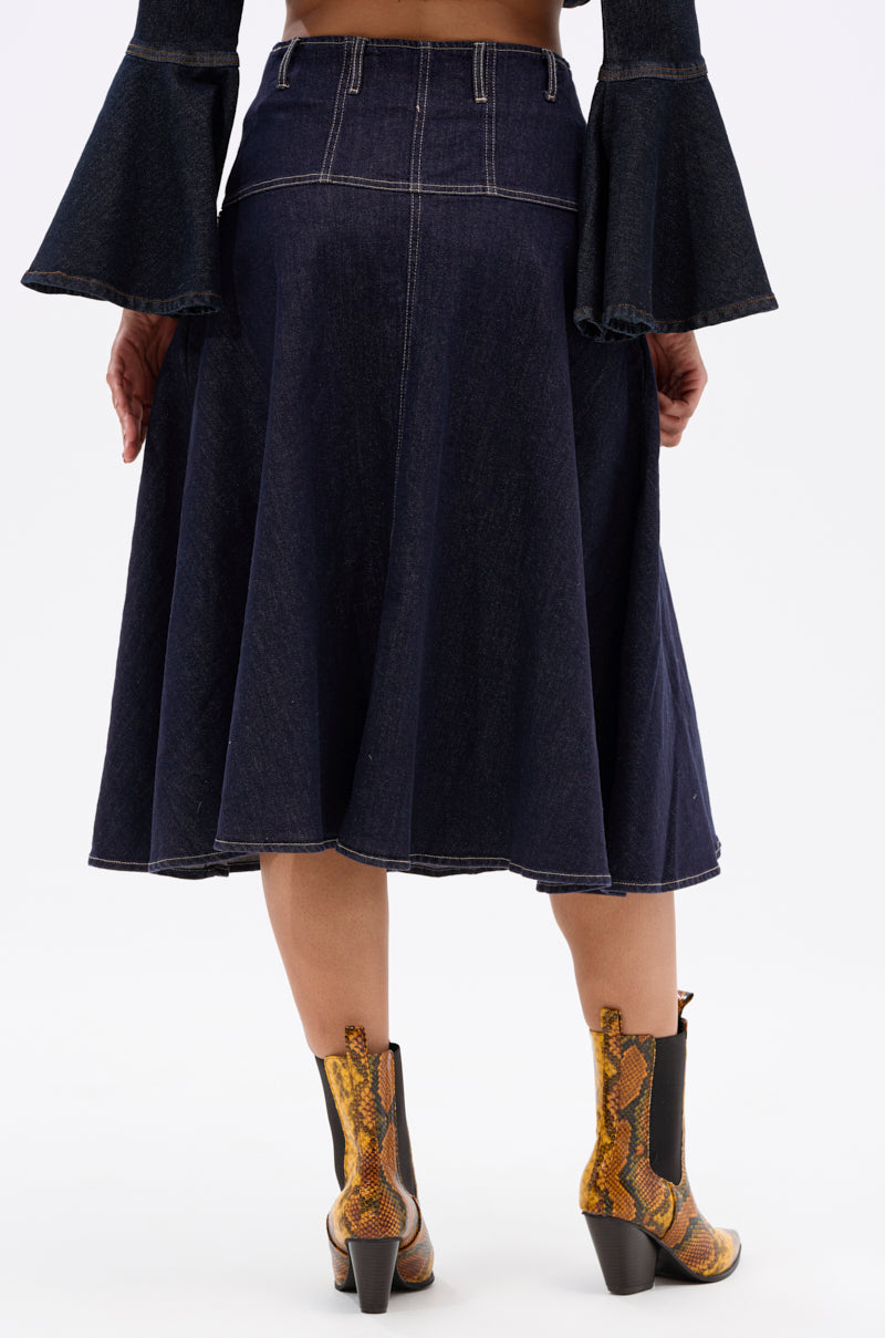A person wearing the COME WITH ME DENIM MIDI SKIRT, a top with flared sleeves, and brown snake-print block heel ankle boots, seen from the back against a plain white background.