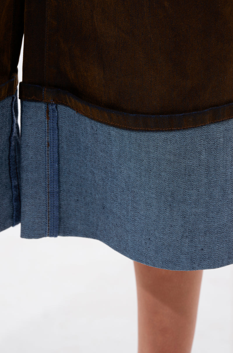 The FALL VIBES VELVET BERMUDA SHORT showcases brown velvet fabric with light blue denim at the hem, making it a chic fall fashion choice. Shown here on a person standing against a plain background.