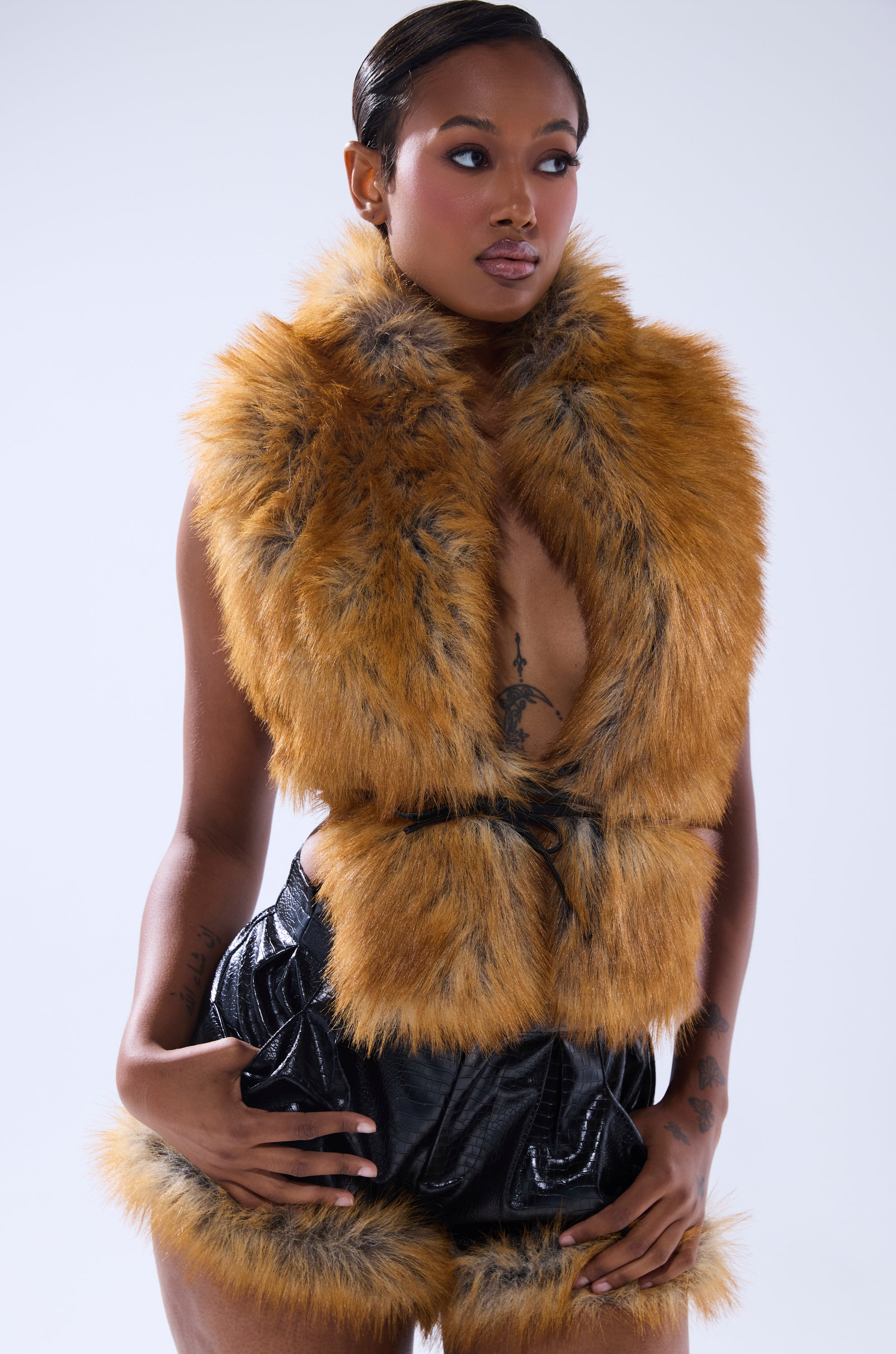 A woman poses for a picture wearing the DONT TOUCH OR LOOK FUR BLOUSE, styled under a golden brown vest.