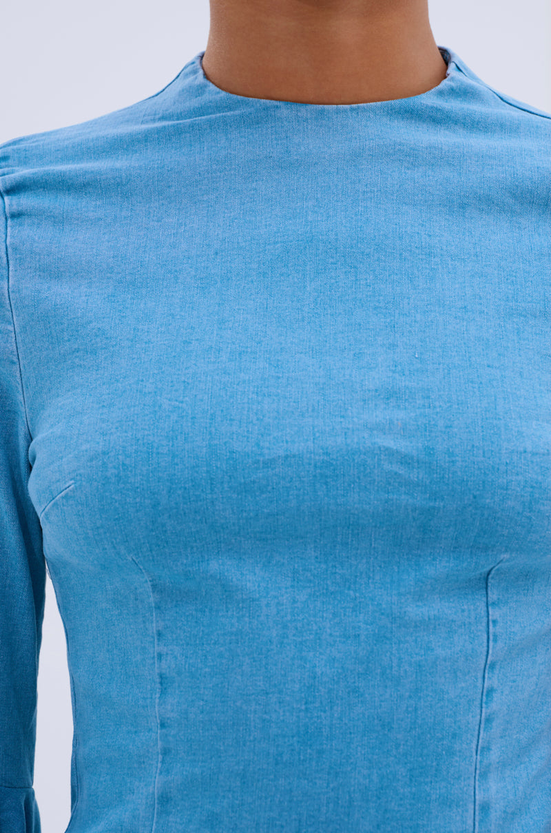 Close-up of a person wearing the SHE'S ROYAL DENIM LONG SLEEVE MINI DRESS, featuring textured light blue denim and bell sleeves. The image focuses on the upper chest, neck, and shoulders; the face is not visible.