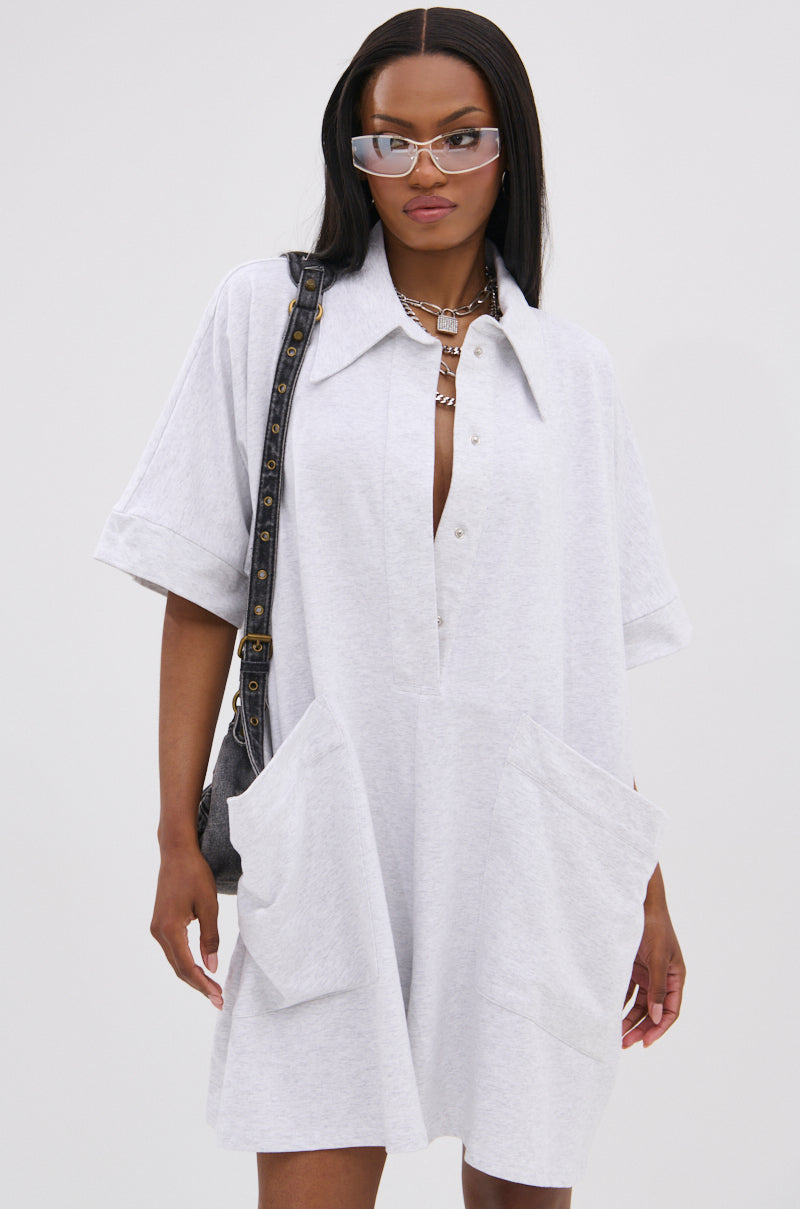 A woman embodies effortless luxury in the SHE'S RICH OVERSIZED FRENCH TERRY ROMPER, styled with oversized sunglasses, layered necklaces, and a black shoulder bag—perfect for all-day comfort against a plain white background.