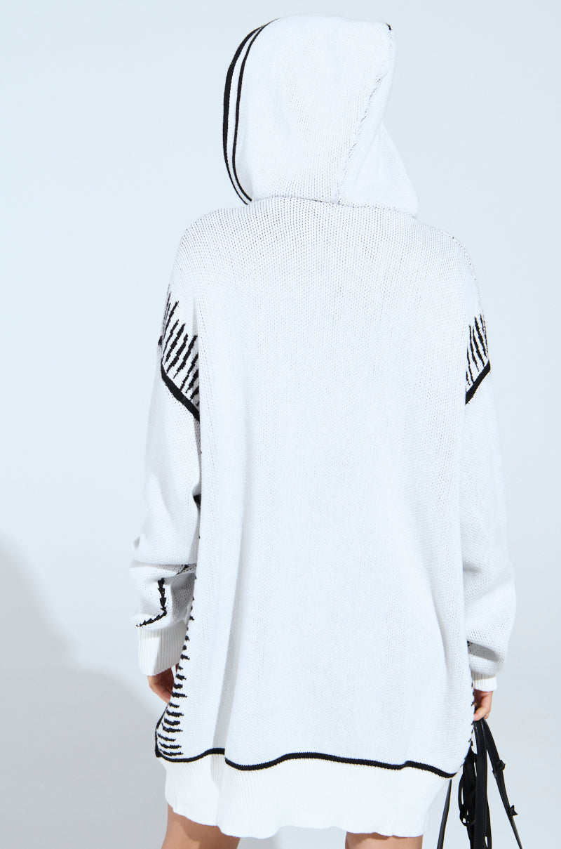 Wearing the SKETCH IT KNIT SWEATSHIRT DRESS with black stripe accents, a person is seen from behind against a plain backdrop. They hold a black bag in their left hand, highlighting the ensemble's artsy trim details.