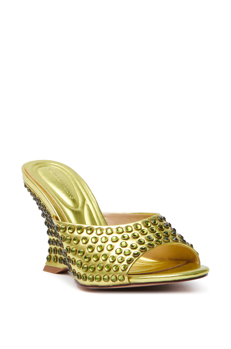 The AZALEA WANG JUNIUS GOLD EMBELLISHED WEDGE SANDAL features a faux leather open-toe design with green studs and a uniquely curved heel, adding an elegant and stylish touch.