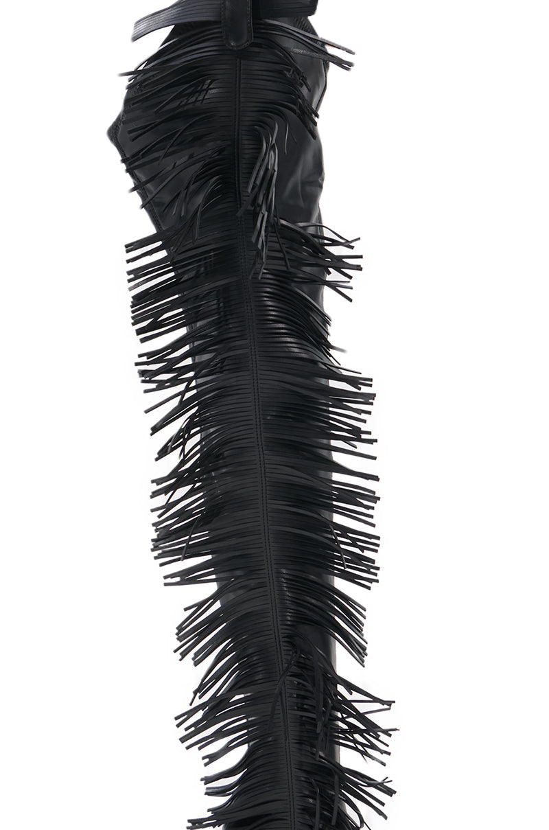 A close-up of the AZALEA WANG KARTICE BLACK STILETTO WESTERN CHAP BOOT in shiny faux leather, featuring long, thin fringe detailing that runs vertically along the side.