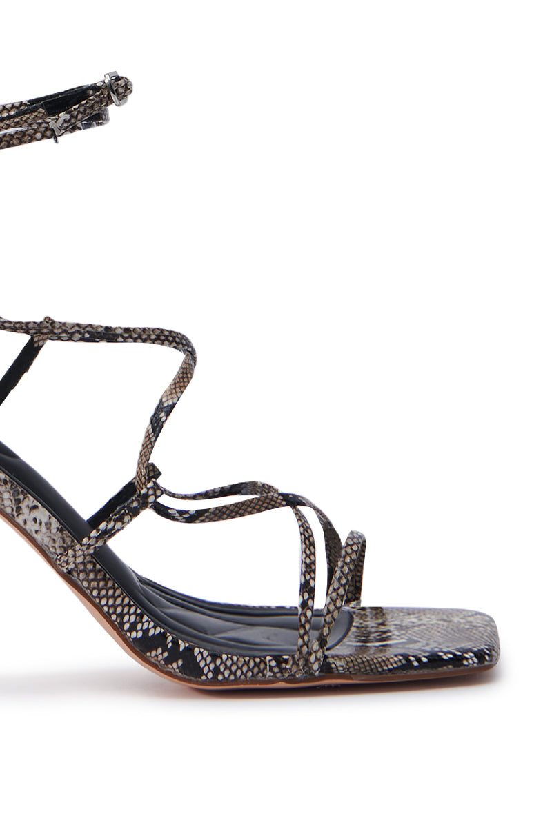 The AZALEA WANG KAYLIN SNAKE SANDAL features a side view of a snakeskin-patterned high heel, with multiple thin straps, a square toe, and an ankle strap for support. This sandal has a moderately high, slim stiletto heel, ideal for making a bold statement.