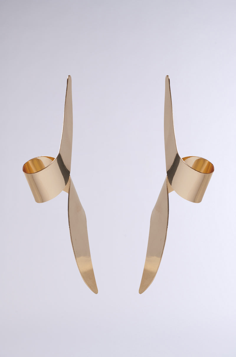Introducing the TWISTED UP EARRING: abstract gold-toned metal earrings with an asymmetrical silhouette and pointed spiral features. Sleek and reflective, these faux metallic gold sculptures pop against a plain gray background.