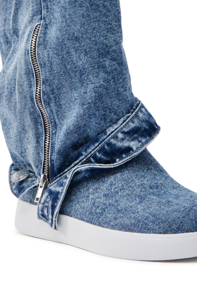 The AZALEA WANG KIMIKA DENIM BOOTIE showcases a unique design with a side zipper, pant leg-like fabric overlay, almond toe, and white rubber sole, creating a fashion-forward sneaker style.