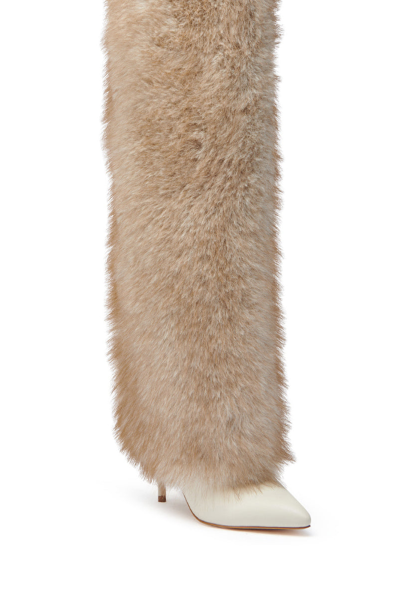 Someone wears the AZALEA WANG LAGANN BONE THIGH HIGH FUR LUXE BOOT, a tall, fluffy light brown faux leather boot covering most of the leg and showing only the pointed toe of a white low-heeled shoe.