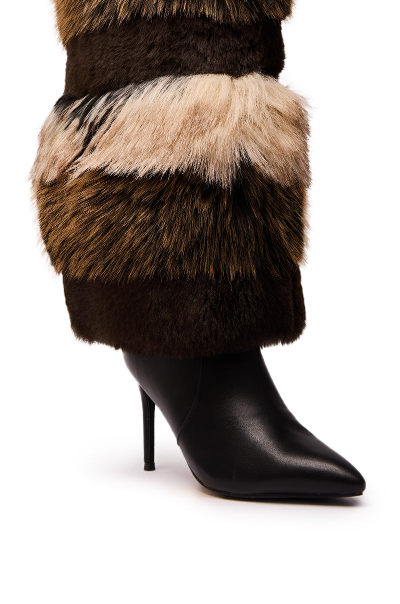 A close-up of the AZALEA WANG LANGLAU BROWN MULTI STILETTO FUR BOOT features a black leather, thigh-high, pointed-toe boot with thick brown, black, and beige faux fur accents against a white background.