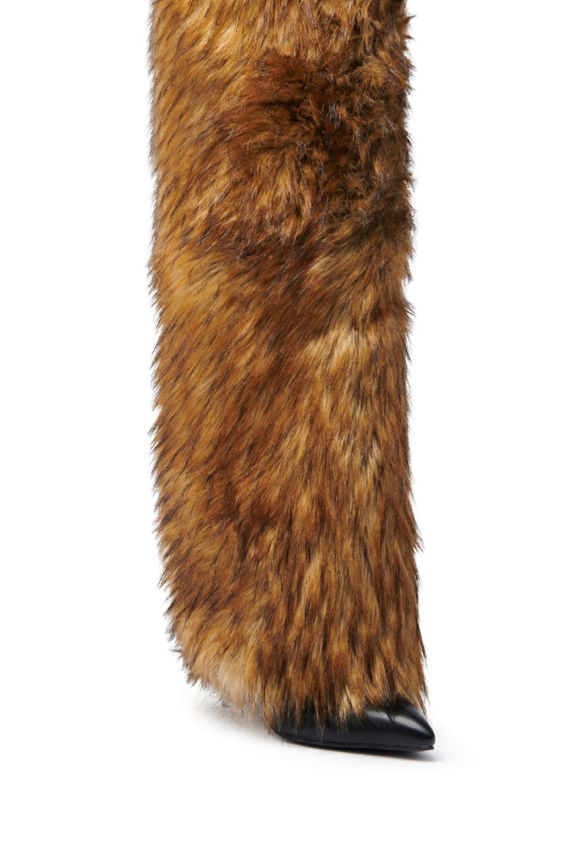 Close-up of a leg in the AZALEA WANG LANGDON BROWN THIGH-HIGH FUR LUXE BOOT, featuring thick brown faux fur extending over most of a pointed black stiletto heel.
