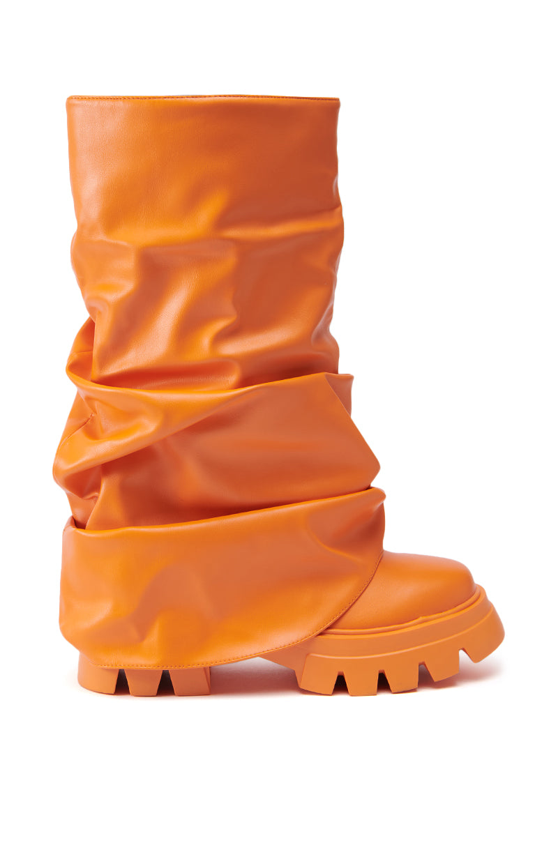 The AZALEA WANG MATE ORANGE BOOTIE, made from faux leather, showcases a slouchy upper and a chunky treaded sole, all presented against a white background.