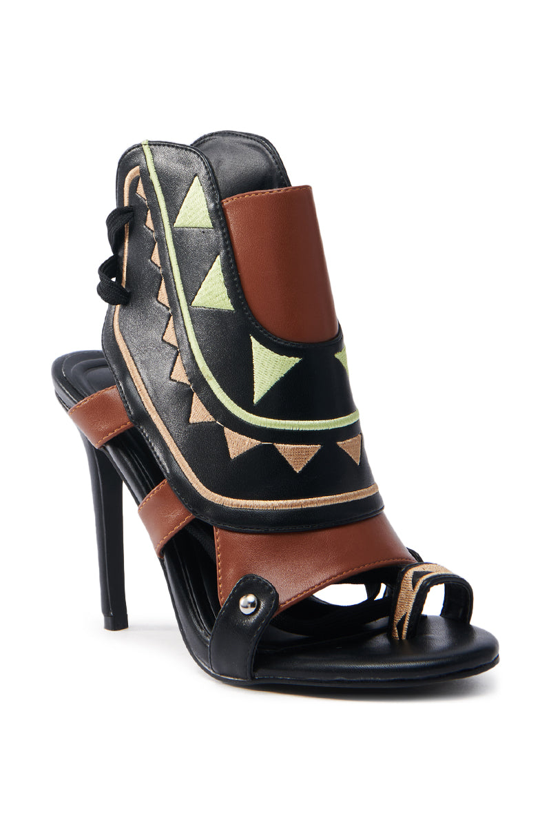 The AZALEA WANG MERAKI BLACK AND BONE SANDAL is a high-heeled stiletto crafted from vegan leather with a color block pattern in black, brown, and beige. It features geometric triangles and circles, an open toe design, and front straps for added elegance.