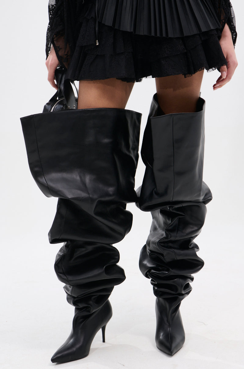A person wears the AZALEA WANG NEMY BLACK KITTEN HEEL THIGH HIGH BOOT, styled with a black pleated mini skirt, against a plain white background.