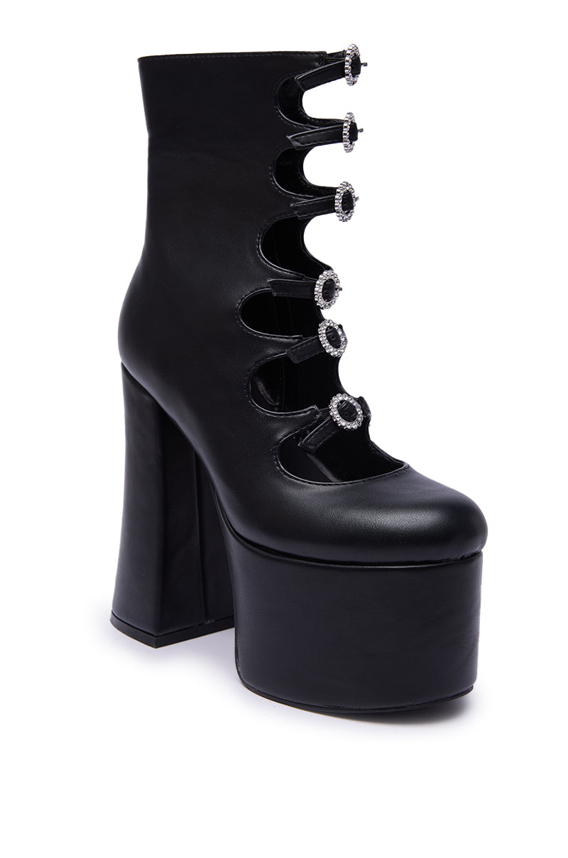 The AZALEA WANG OMLEE BLACK ULTRA HIGH PLATFORM BOOTIE features black faux leather, a chunky high heel, and five decorative strap closures with round jeweled buckles up the front.