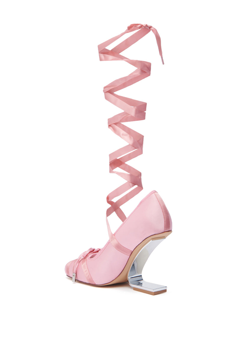The AZALEA WANG PAVARTI PINK BALLET PUMP features a satin upper, pointed toe, ribbon laces that wrap up the leg, and a unique silver inverted wedge heel, shown against a white background.