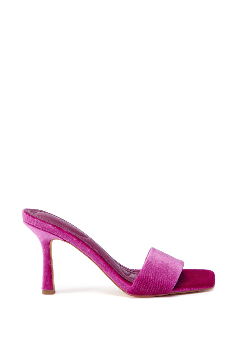 The AZALEA WANG PERSUASION FUCHSIA SANDAL features a single velvet heel in fuchsia with an open toe and a thin strap across the foot. It has a sleek, moderately high stiletto heel, and the interior is lined with coordinating pink material. The sandal is displayed against a plain white background.