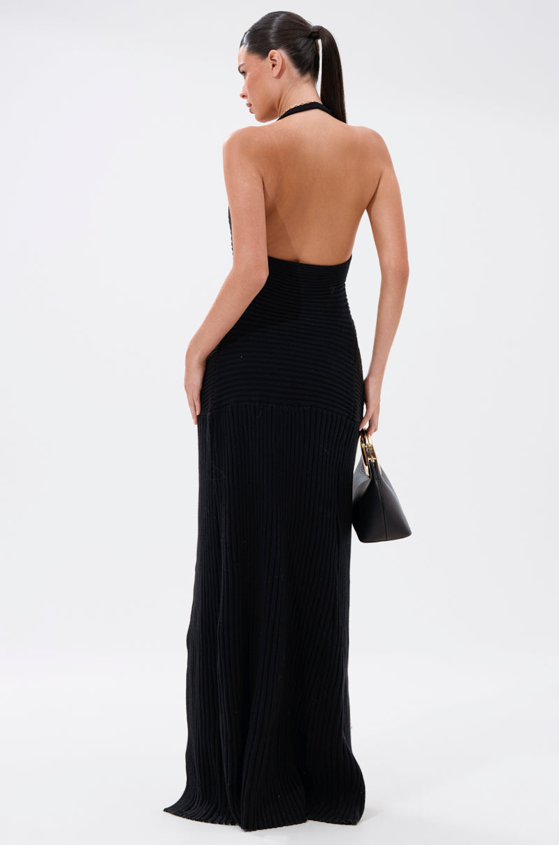 A woman with a ponytail wears the TIED TO YOU TIE-FRONT SWEATER and holds a black handbag. She stands facing away from the camera against a plain, light background.