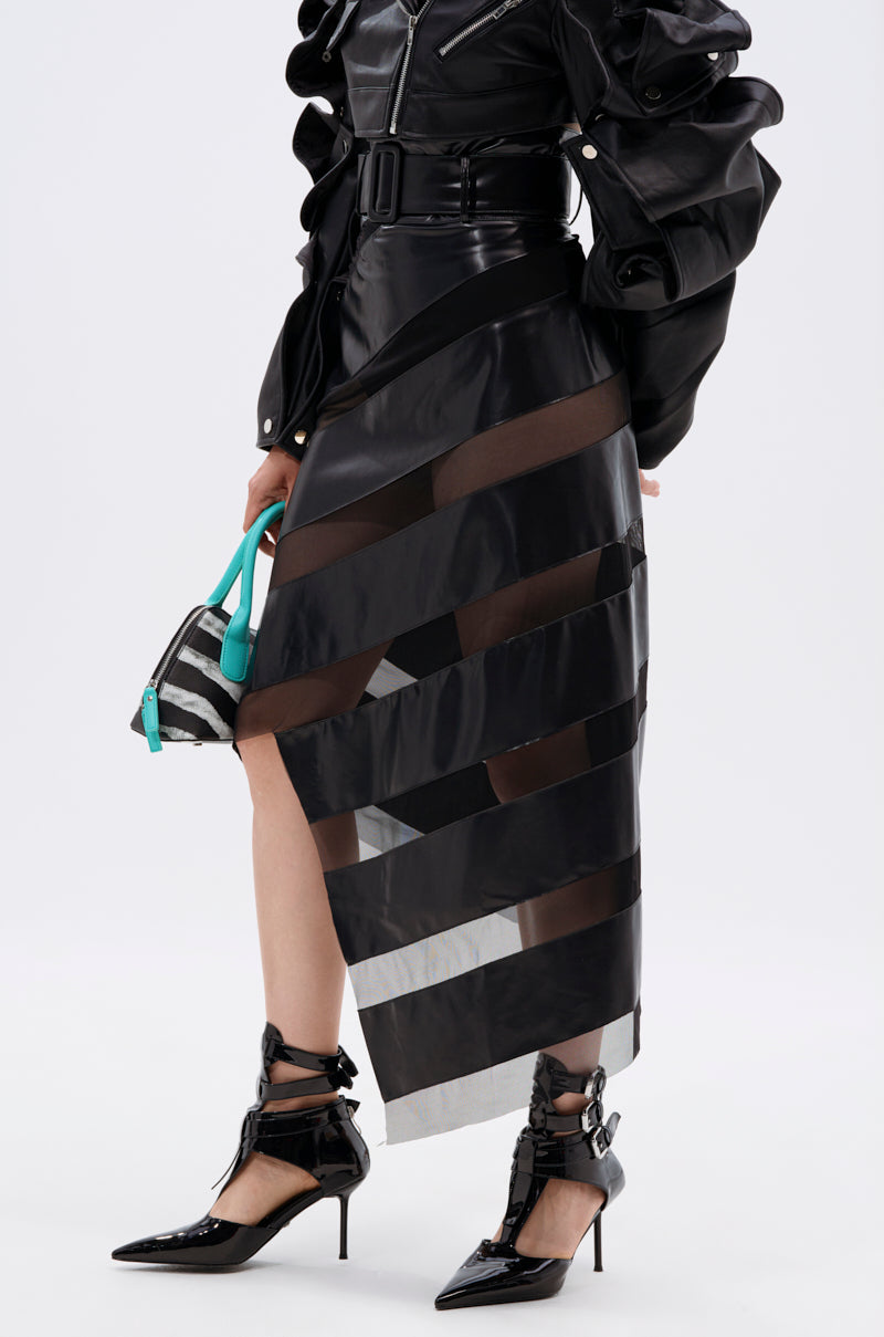 Wearing a black belted long-sleeve top and the SOMETHING DIFFERENT MESH MIDI SKIRT WITH FAUX LEATHER featuring asymmetrical sheer panels, paired with black pointed heels and a zebra-print bag with teal handles.