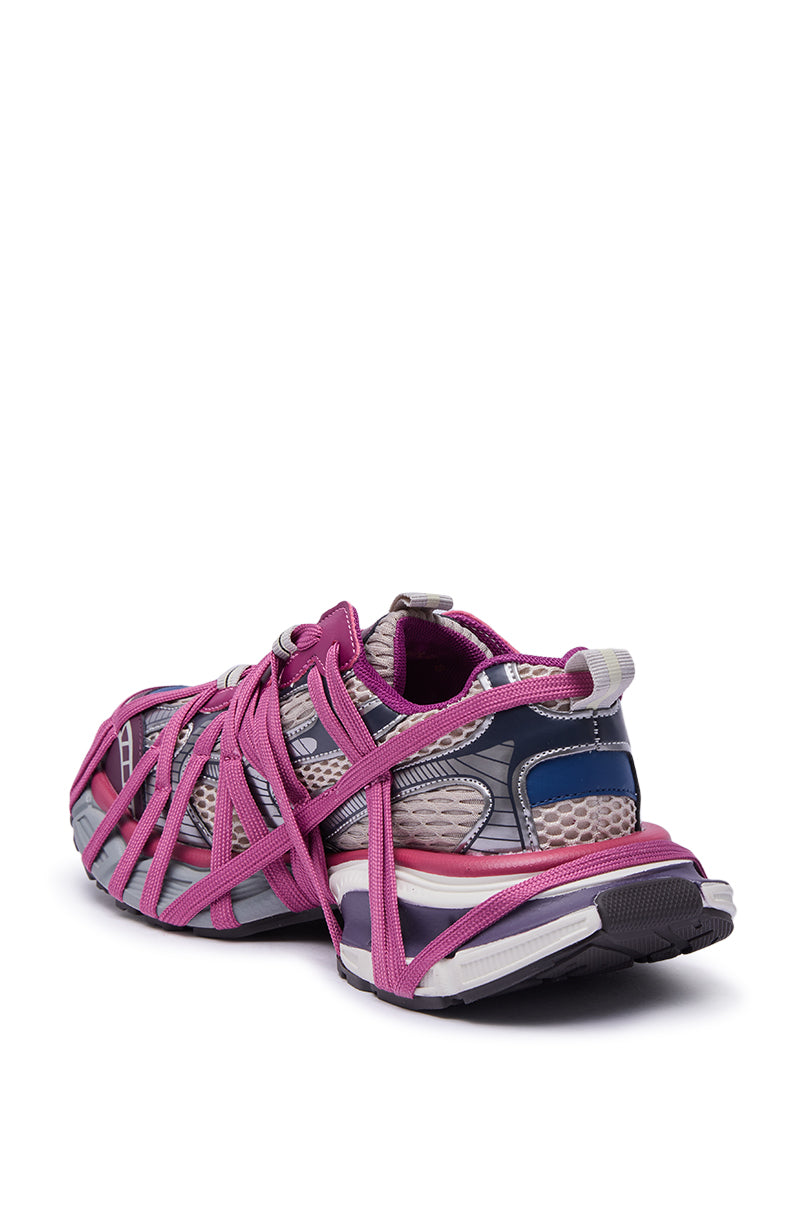 The AZALEA WANG SELIE PURPLE LACE UP SNEAKER is a stylish sneaker in pink, purple, and gray with multiple overlapping pink laces, a thick textured sole, and shown from a rear angled view.