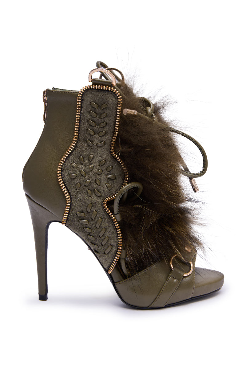 The AZALEA WANG SHAINY OLIVE FUR SANDAL features an open toe, stiletto heel, olive fur accents, decorative gold trim, stitched detailing, and a back zipper closure.