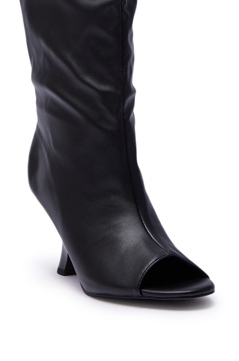 The AZALEA WANG SIZANI BLACK WEDGE SLOUCHY BOOT is crafted from smooth faux leather with a knee-high slouchy design, almond peep toe, and high wedge heel, shown on a plain white background.