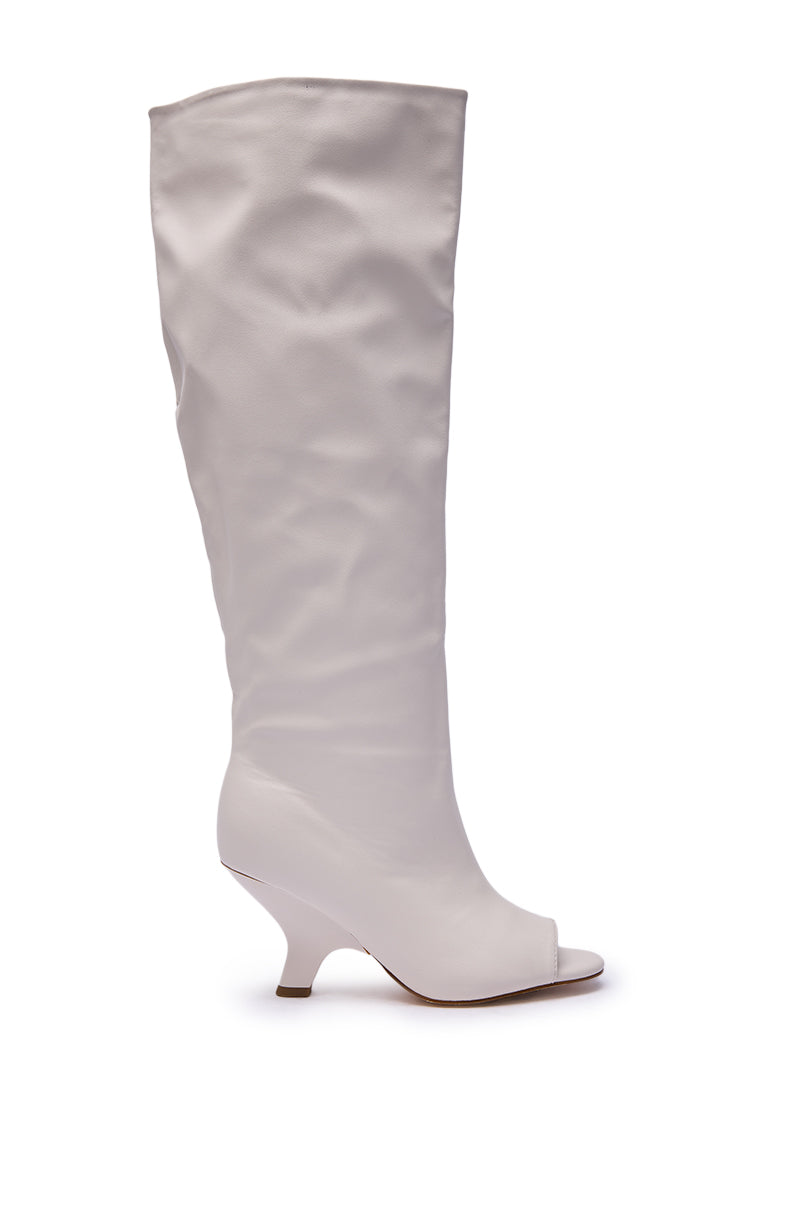 The AZALEA WANG SIZANI WHITE WEDGE SLOUCHY BOOT is a white, knee-high faux leather peep toe boot with a low, curved wedge heel, shown against a plain white background.