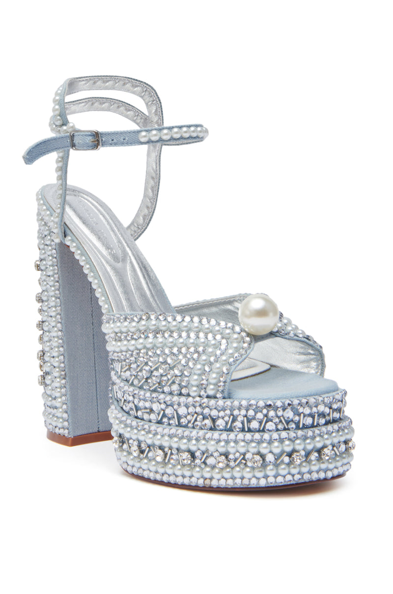 The AZALEA WANG SOMETHING BLUE CHUNKY SANDAL is a light blue denim, open-toe platform heel with an ankle strap, featuring pearl embellishments including a large pearl on the front strap and smaller pearls on the heel and platform.