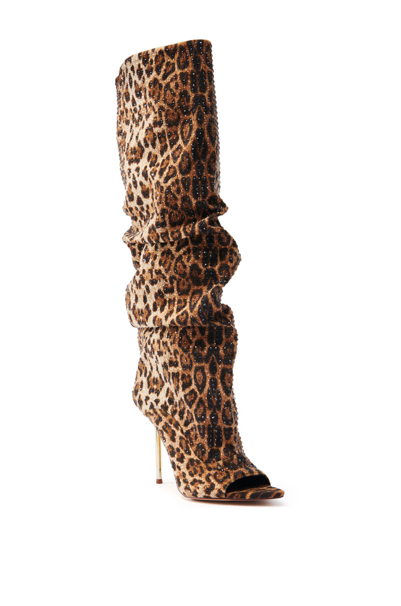 The AZALEA WANG SPHYNX LEOPARD OPEN TOE BOOT is a knee-high, faux suede boot featuring a chic leopard print and a slouchy fit, complemented by a thin stiletto heel.