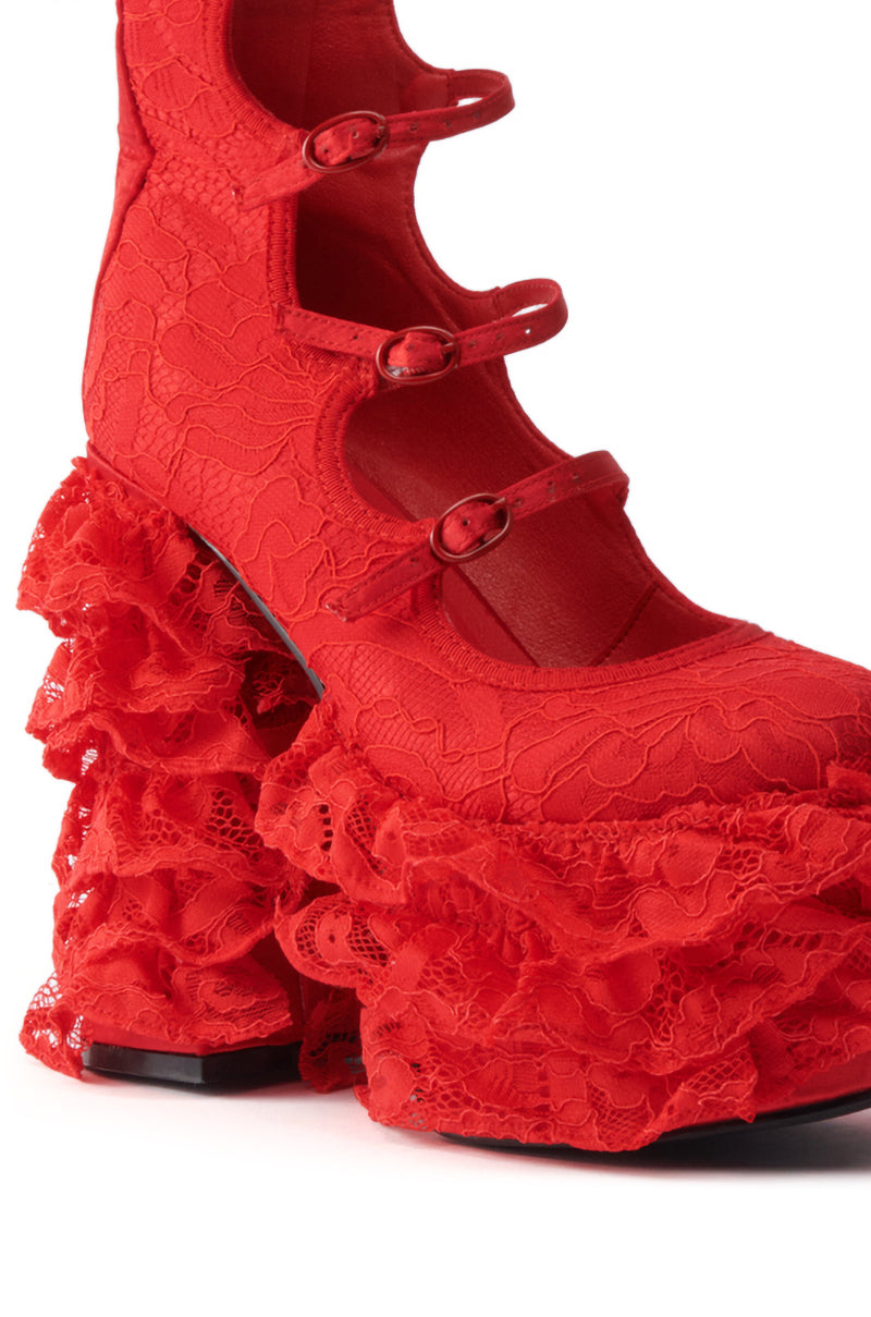 Close-up of the AZALEA WANG SPREENE RED CHUNKY PUMP, a bold red shoe with an almond toe, three buckled straps, lace fabric, and a chunky heel detailed with layered ruffles.
