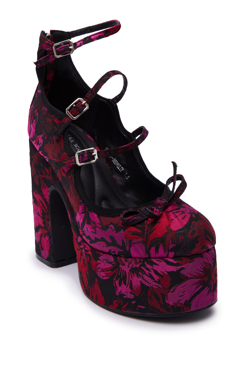 The AZALEA WANG SPROUT Red Multi Floral Brocade Mary Jane Platform Pump features a chunky heel, vibrant red and pink floral brocade, three buckle straps, and a small bow on the rounded toe.