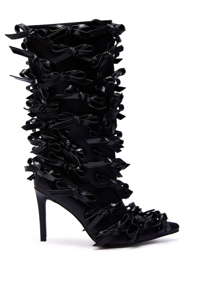 The AZALEA WANG TELMO BLACK BOW EMBELLISHED BOOTIE is a knee-high, pointed-toe stiletto bootie featuring dramatic black ribbon bows all over for a bold statement look.