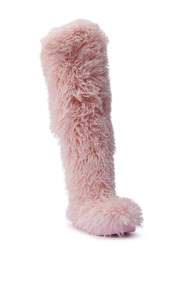 The AZALEA WANG TEMPLETON PINK POODLE FAUX FUR OVER THE KNEE BOOT, crafted from shaggy pink faux fur in a chic poodle design, stands elegantly against a crisp white backdrop.