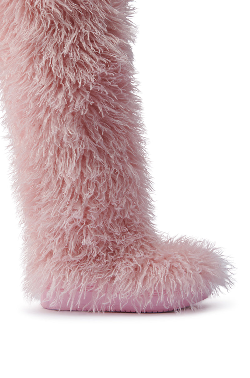 A close-up of the AZALEA WANG TEMPLETON PINK POODLE FAUX FUR OVER THE KNEE BOOT showcases its textured, fluffy outer surface and smooth pink sole. With their soft, plush appearance and shaggy design, these boots have a whimsical look.