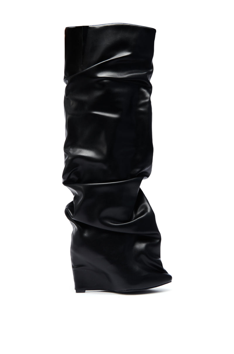 The AZALEA WANG TEUILA BLACK RUCHED WEDGE BOOT features a slouchy knee-high shaft, pointed toe, hidden wedge heel, and is crafted from shiny black faux leather with ruched detailing.