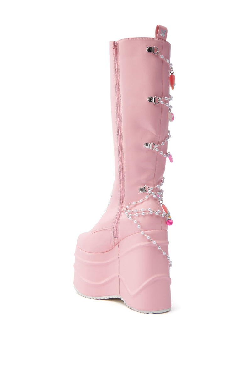 KOI FOOTWEAR THE DREAMSCAPE NOVELTY PINK FLATFORM BOOT is a tall pastel pink faux leather boot featuring a chunky sole, side zipper, and decorative pearl-like beads and charms. Shown on a plain white background.