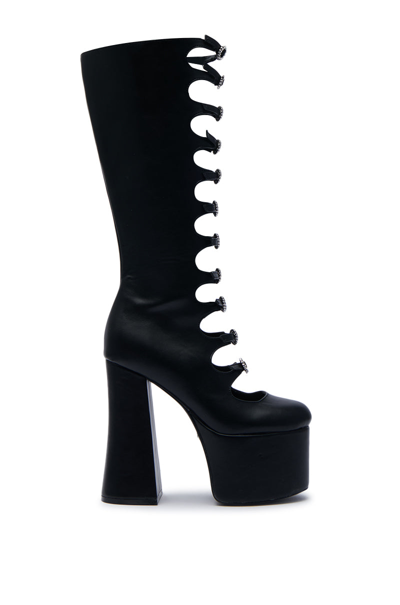 The AZALEA WANG TOMLIN BLACK BOOT is a faux leather, knee-high boot with a chunky platform heel and an open lace-up design, featuring seven circular cut-outs along the front.