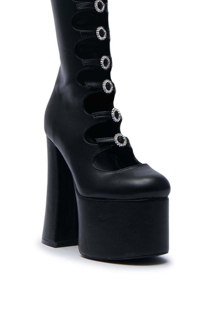 Introducing the AZALEA WANG TOMLIN BLACK BOOT: a striking high-heeled platform boot featuring multiple circular cutouts and rhinestone-style embellishments along the front. Crafted from sleek faux leather, these chic, chunky heel boots offer an edgy mid-calf style, beautifully set against a plain white background.