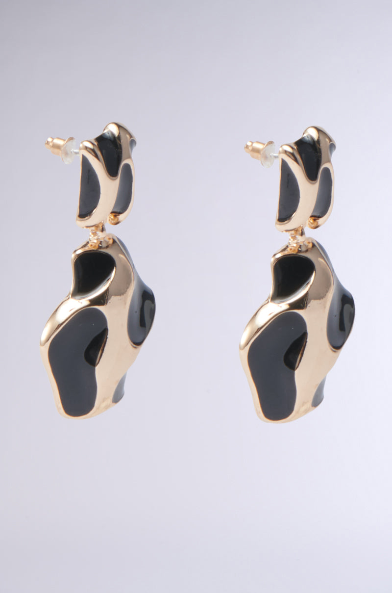 The FOR THE VIBES EARRING features faux gold dangle pendants with glossy black accents in abstract, curved shapes, creating a modern and artistic look against a light gray background.