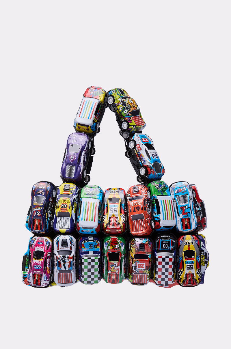 The I GO FAST RACE CAR PURSE is a playful handbag crafted from colorful toy cars arranged in a pyramid shape, featuring a handle made of toy cars, displayed against a plain white background.