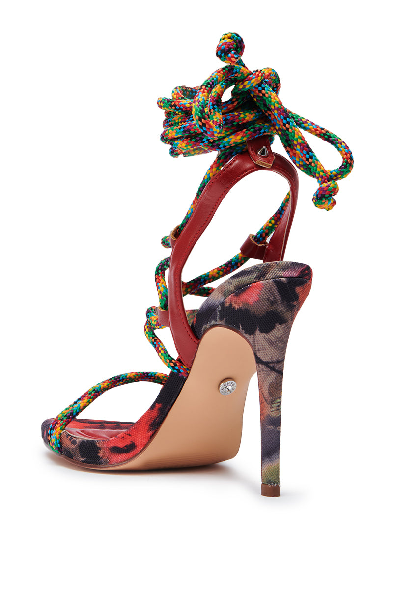The AZALEA WANG TZILLA MULTI COLOR ROPE STILETO SANDAL showcases a multicolored rope lace-up design, floral fabric, red interior, beige sole, and a round gemstone at the heel.